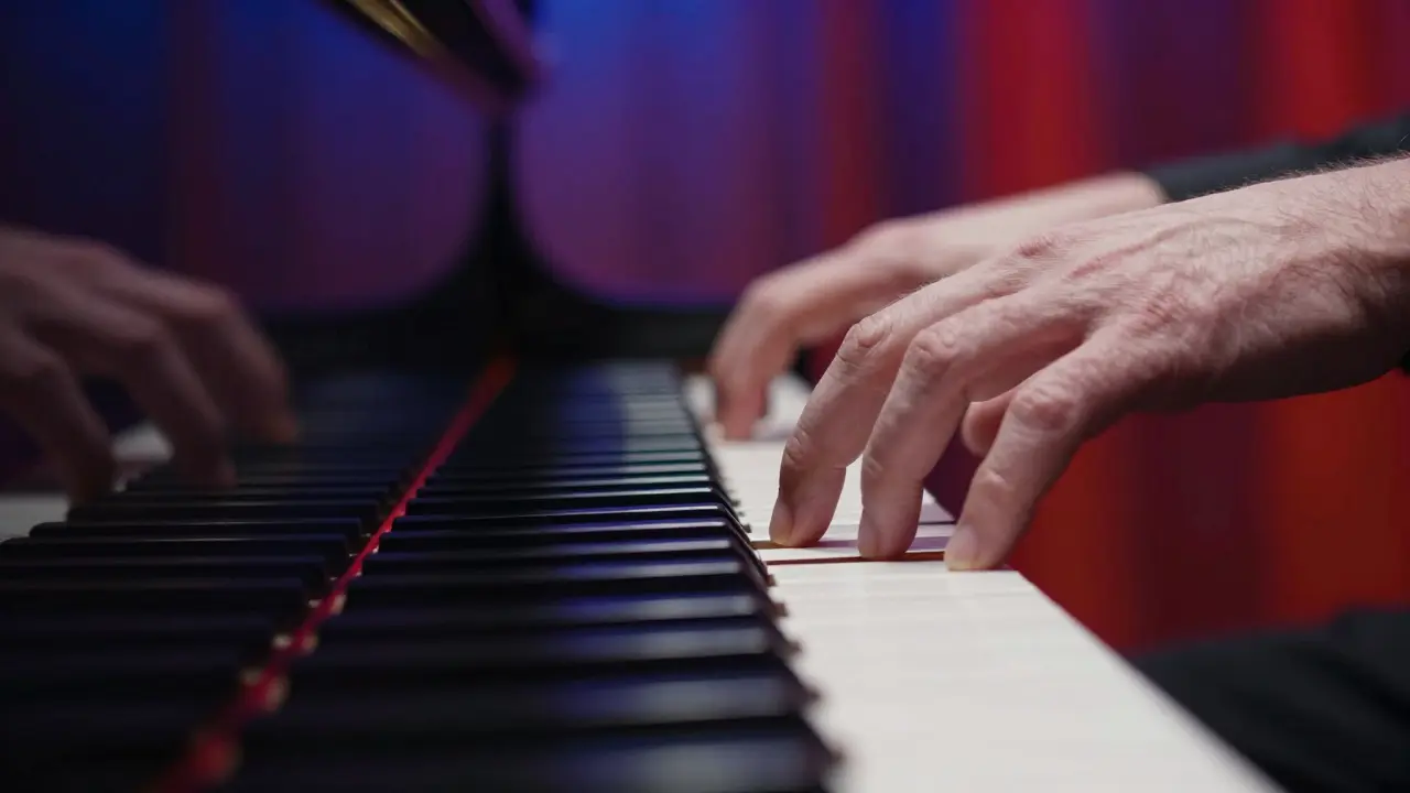 Close-up of pianist hands poised over keys with dramatic lighting